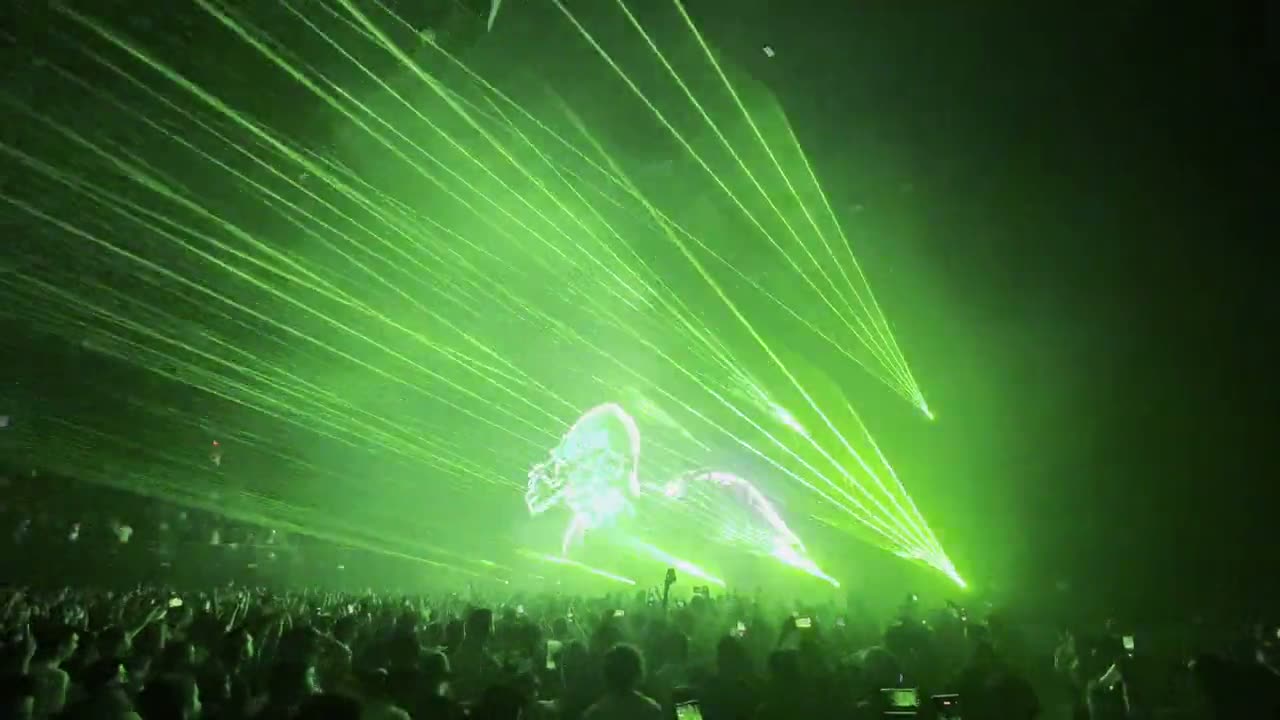 Haces de láser verde abriéndose sobre el público de un concierto