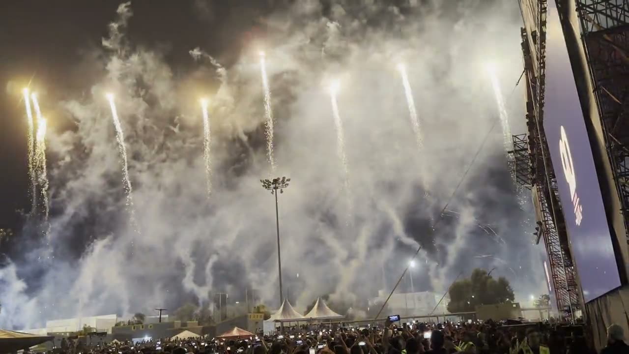 Cascadas de pirotecnia disparadas sobre un estadio lleno en un evento nocturno