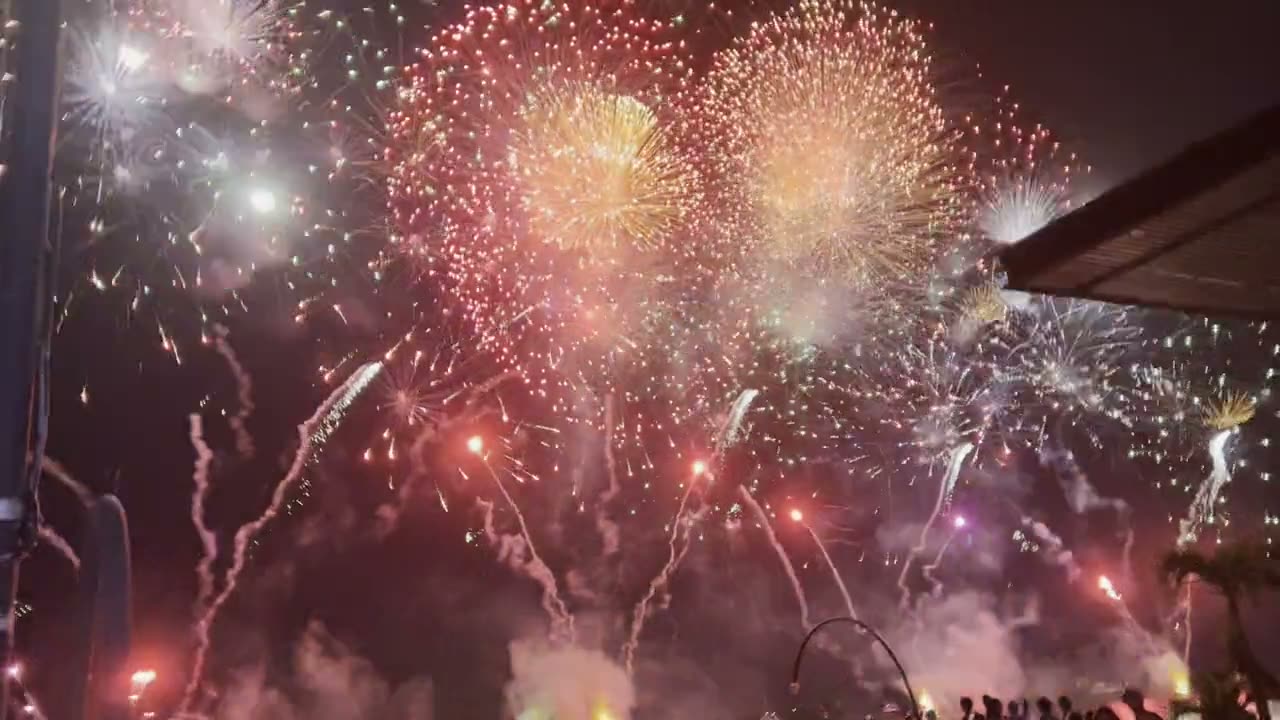 Fuegos artificiales de colores abriéndose sobre el público de una celebración nocturna